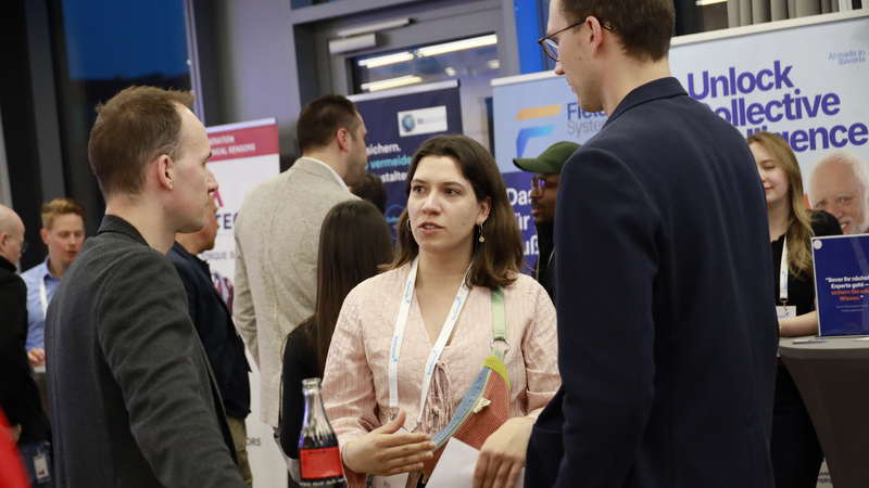 Eine Frau und zwei Männer unterhalten sich inmitten der Networking Area des B2B-DemoDays